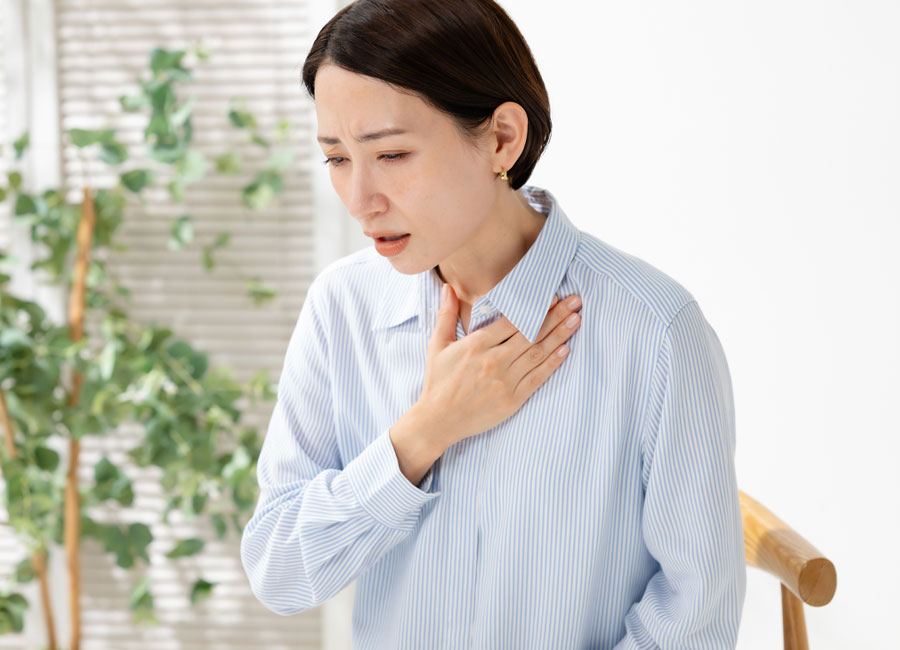 動悸息切れ胸を抑える女性